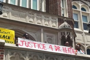 Students hold a banner that says "Justice 4 Dr. Heath" at a protest to save Scott Heath's job at Loyola University New Orleans.