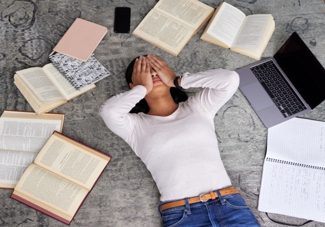 High angle shot of an unidentified young female student looking stressed while studying in the library - stock photo