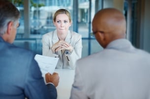 Anxious woman looks at two men interviewers with their backs to the viewer